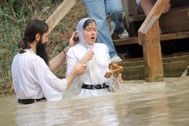 Scaerdote ortodosso amminitsra un battesimo nel Giordano